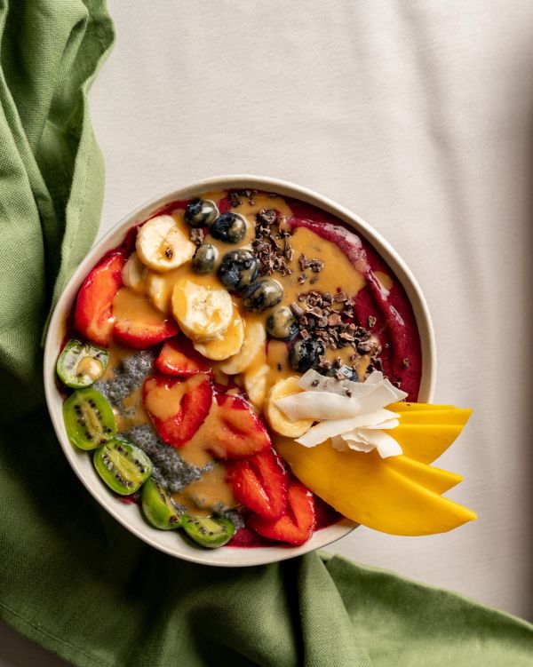 Cremig gemixte Açaí Bowl mit Fruchttoppings auf hellem Tuch