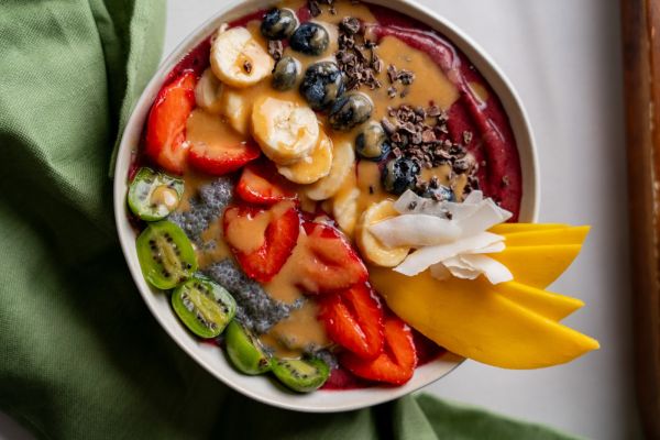 Açaí Bowl von oben mit Erdbeeren, Banane, Blaubeeren, Mango, Mini-Kiwi, Chiasamen und Nussmus