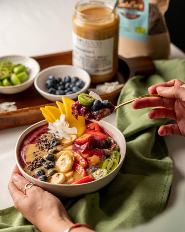 Löffel mit violetter Açaí-Masse über einer angerichteten Bowl
